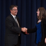 Doctor Smart shaking hands with an award receipient in a blue shirt and black sweater
